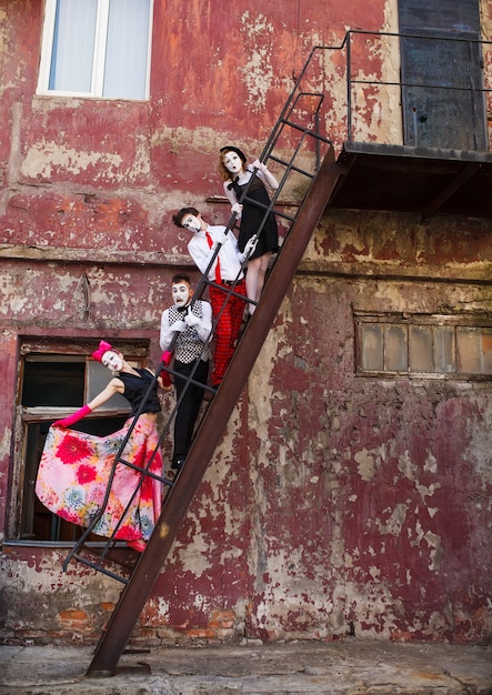 Four Mimes standing on the stairs on a red wall.