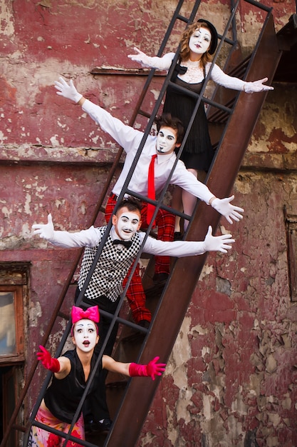 Four Mimes standing on the stairs on a red wall.