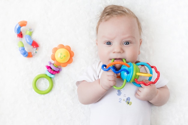 Four-month-old boy chewing a rattle a white