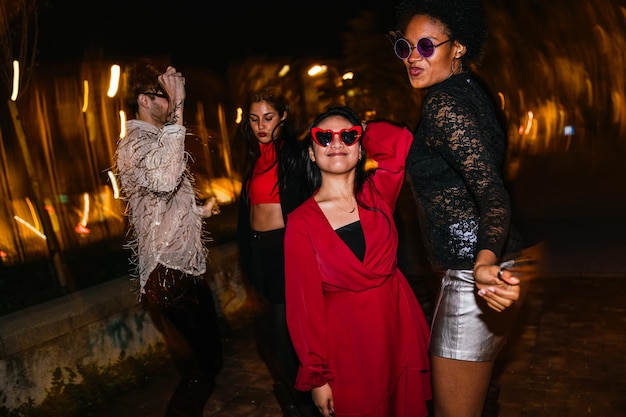 Photo four multiethnic friends partying at night playful poses stylish wear and joyful ambiance