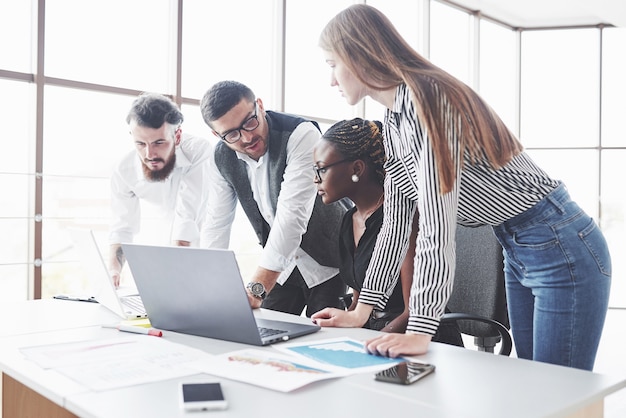 Four multiracial employee have work in the office using the laptop on table