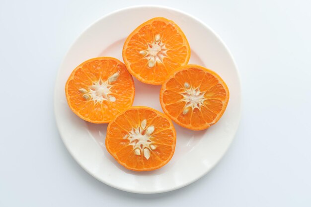 Four orange slices on a plate with one that has seeds on it.