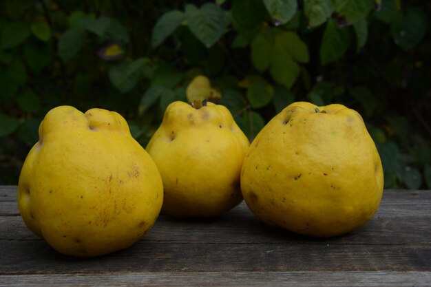 Four pears sit on a wooden table with a green background.