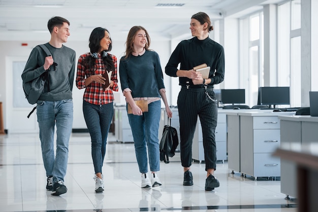 Four people. Group of young workers walking in the office at their break time.