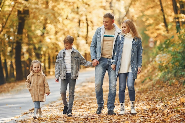 Quattro persone la famiglia felice è insieme nel parco in autunno