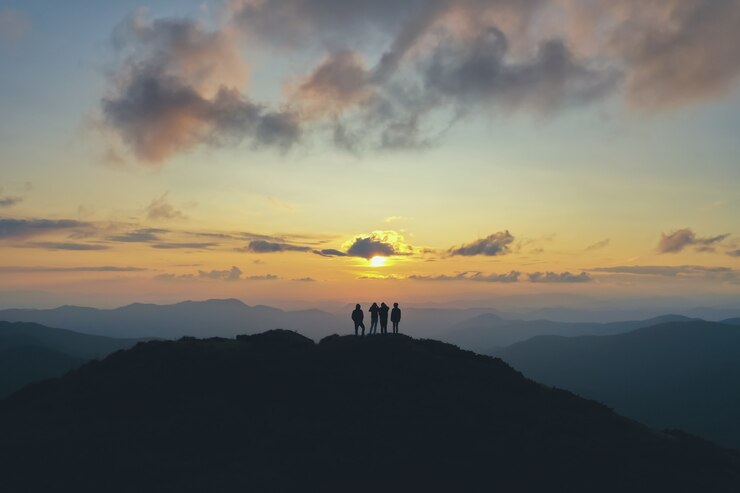 夕日を背景に美しい山に立つ4人