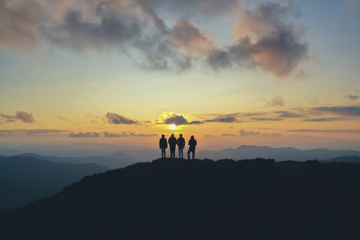 夕日を背景に美しい山に立つ4人