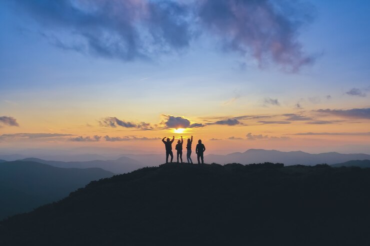 夕日を背景に美しい山に立つ4人