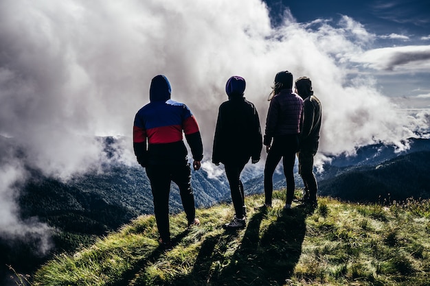 Foto le quattro persone in piedi su una montagna contro bellissime nuvole