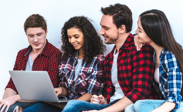 The four people with a laptop sitting on the white wall background