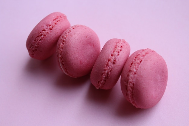 Photo four pink macaroons on a light pink background, minimal food concept