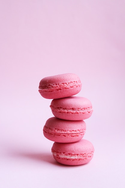 Four pink macaroons on a light pink background, sweet minimal food concept