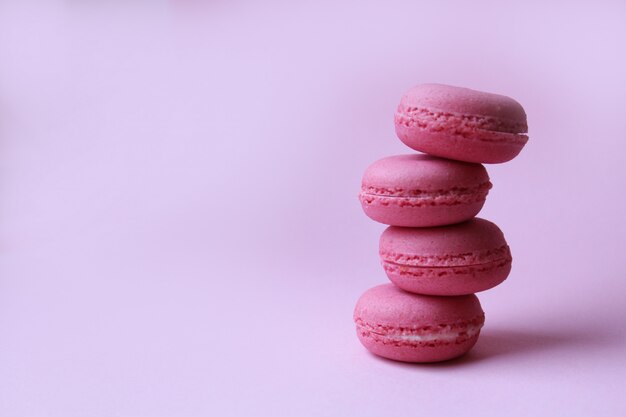 淡いピンクの背景、甘い最小限の食品のコンセプトに4つのピンクのマカロン