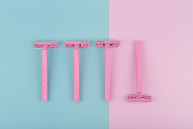 Four pink razors on colored background