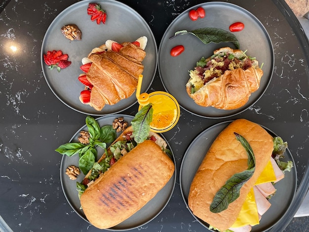 Фото Четыре тарелки с едой, включая бутерброды, одна с лимоном.