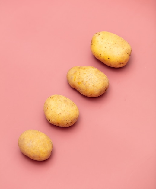 Four potatoes on pink background