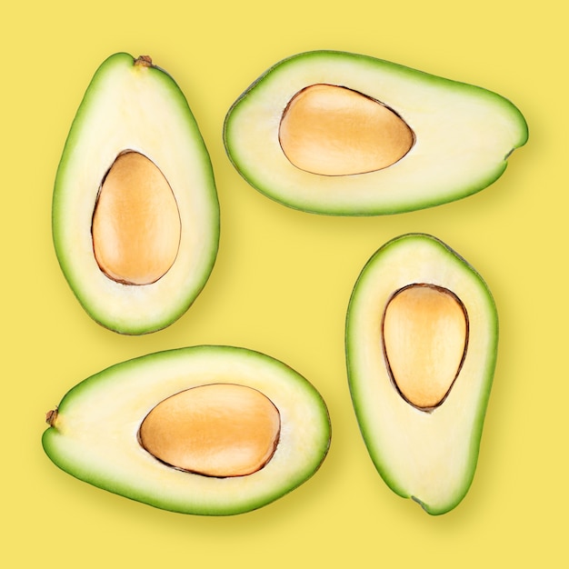 Quattro metà mature dell'avocado su fondo giallo. per lo sfondo viene utilizzato il colore pantone del 2021: 13-0647 illuminante.