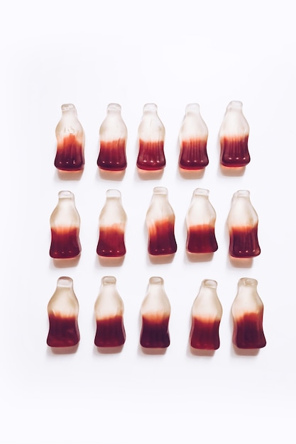 Four rows background of cola flavoured and bottle shaped gummy jelly candies