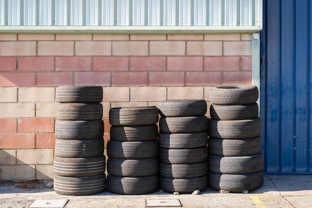 Four rows of used car wheels next to the workshop wall