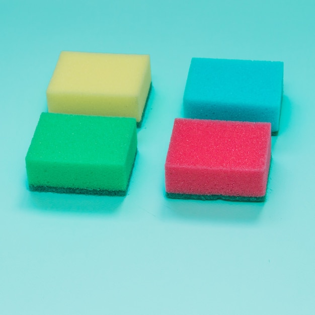 Four sponges in different colors on blue background
