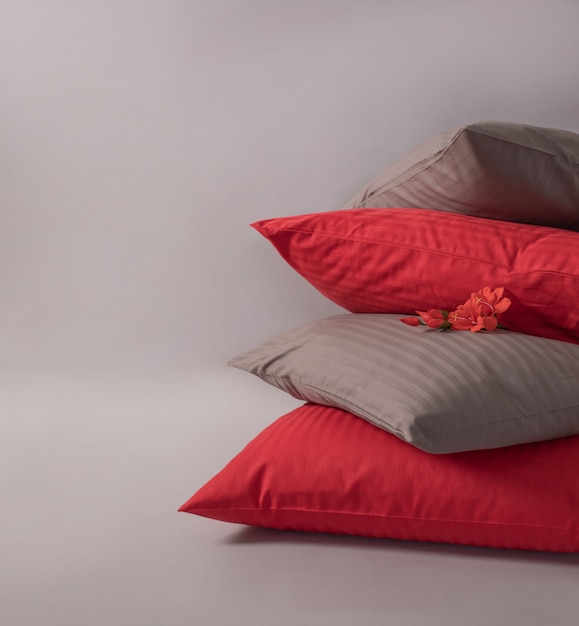 Four stacked cushions with red flower against the white background.