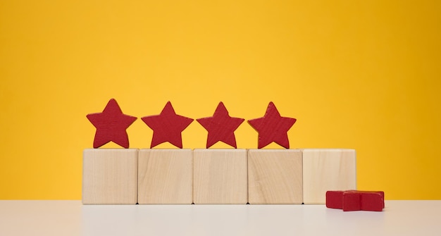 Four stars on wooden cubes yellow background Service evaluation concept high rating