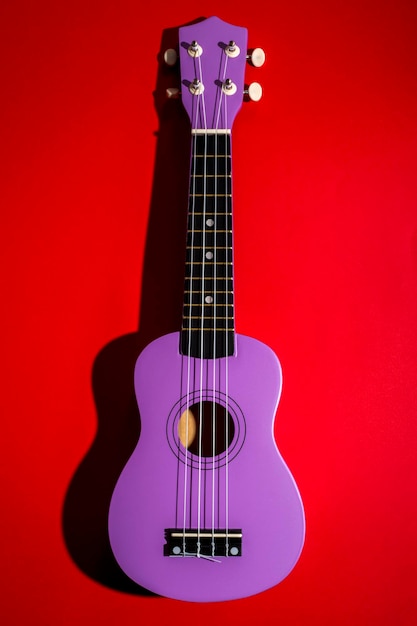 Four string ukulele guitar on red background