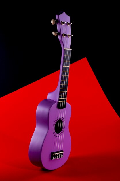 Four string ukulele guitar on red and black background