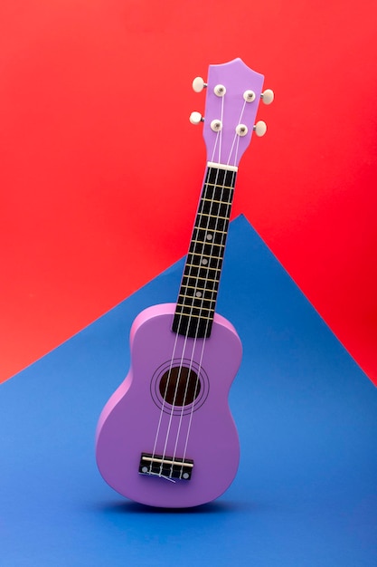 Four string ukulele guitar on red and blue background