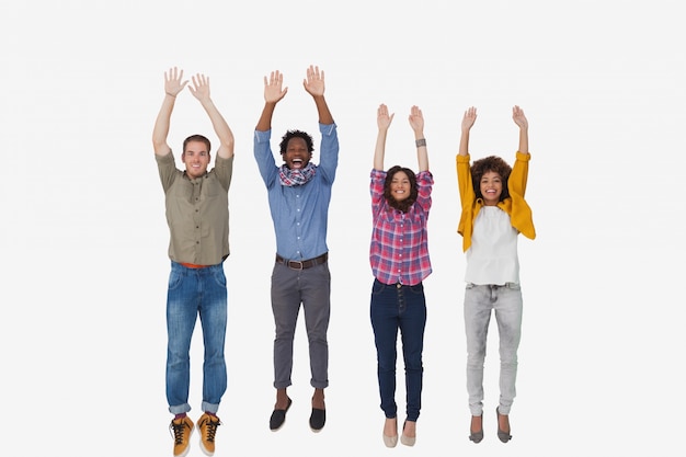 Four stylish friends smiling at the camera and jumping