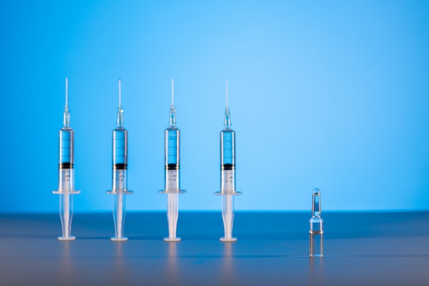 Four syringes scored by a medicinal product and one whole ampoule stand in a row. The concept of pharmacology. 