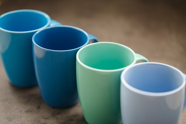 Four tea mugs of different colors on a gray background