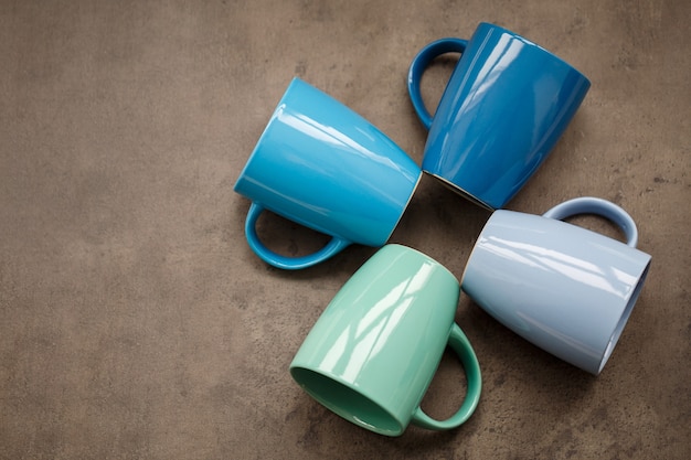 Four tea mugs of different colors on a gray background