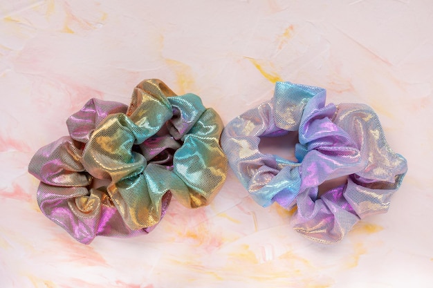 Four trendy holographic scrunchies on pink background