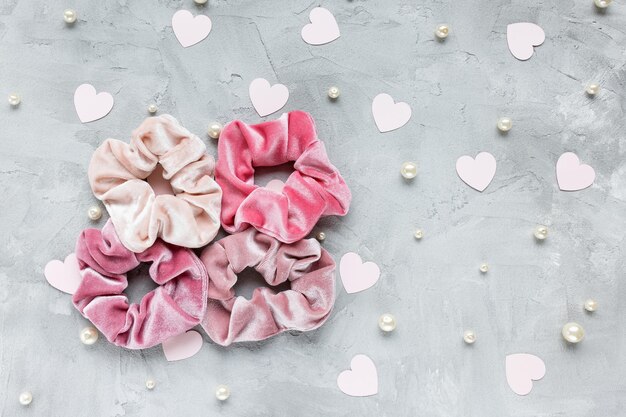 Photo four trendy velvet scrunchies pastel pink paper hearts and white pearls on gray background diy