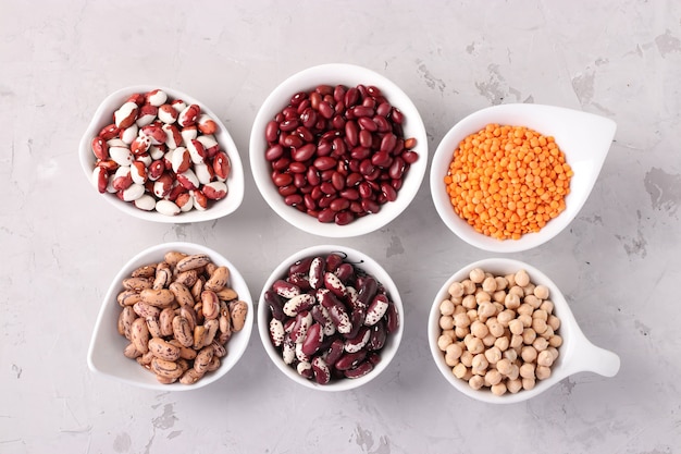 Four varieties of beans, red lentils and chickpeas - protein rich beans are located on a gray concrete background, Top view, Closeup