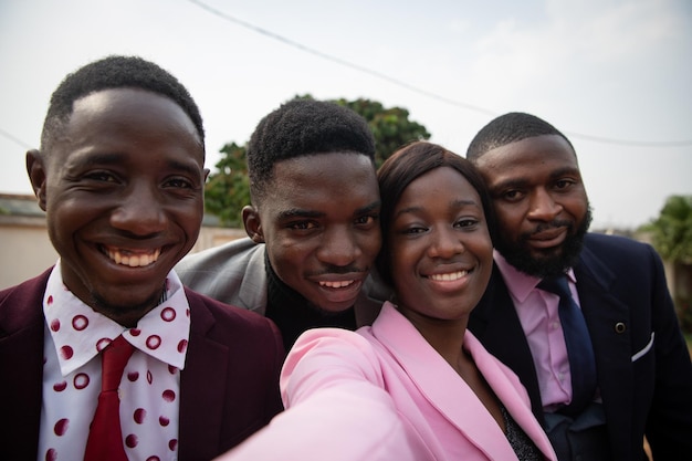 Quattro colleghi africani sorridenti ben vestiti prendono selfie concetto di svago