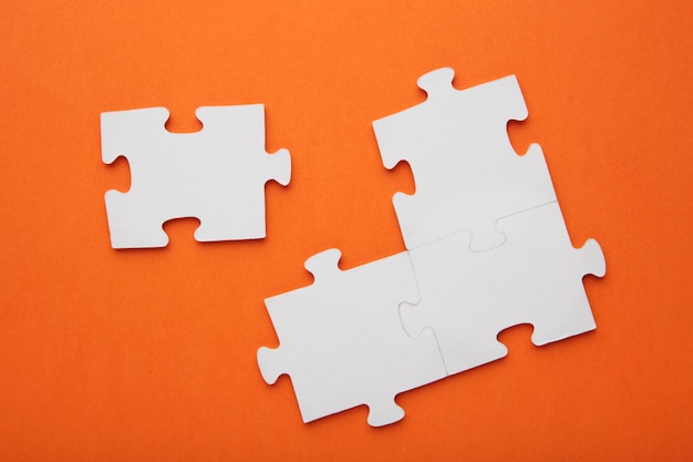 Four white puzzle pieces on orange background