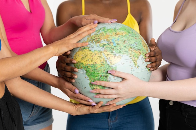 Photo four women hold the globe above in front of them and gently embrace it with their hands