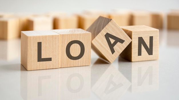 Four wooden blocks with the letters Loan on the bright surface of a gray table, business conceptual word collected of of wooden elements with the letters.