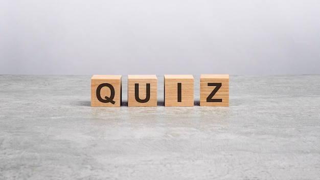 four wooden blocks with the letters Quiz on the bright gray table. business concept