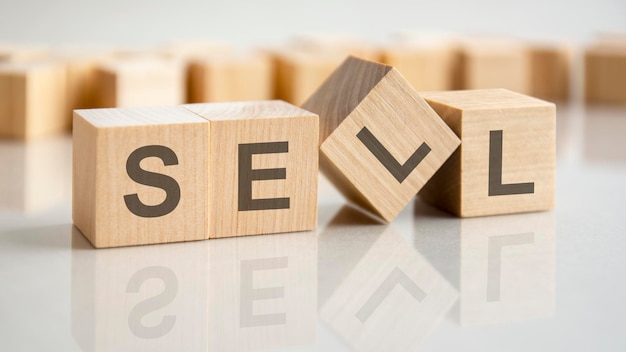 Four wooden blocks with the letters sell on the bright surface of a gray table. the inscription on the cubes is reflected from the surface of the table. business conceptual