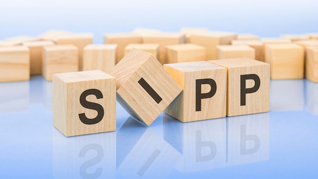 Four wooden blocks with the letters SIPP on the bright surface of a blue background the inscription on the cubes is reflected from the surface business concept