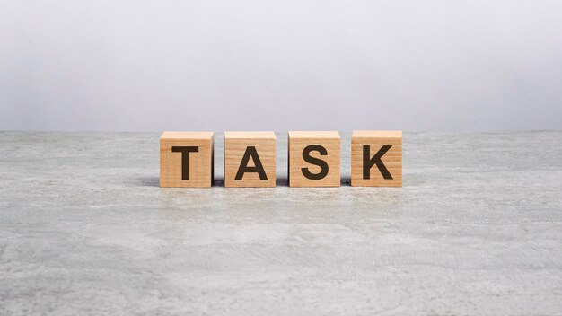 Four wooden blocks with the letters Task on the bright gray table business concept