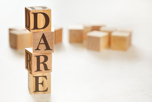 Four wooden cubes arranged in stack with text DARE (meaning Define, Assess, Respond, Evaluate) on them, space for text / image at down right corner