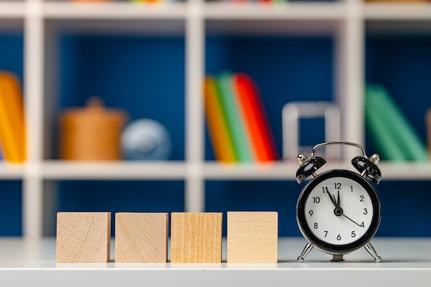 Four wooden cubes with copy space and alarm clock on desk