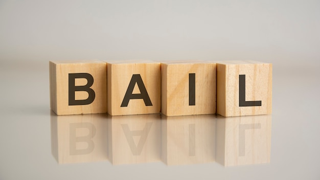 Four wooden cubes with letters Bail. Business marketing concept. Reflection of the caption on the mirrored gray surface of the table