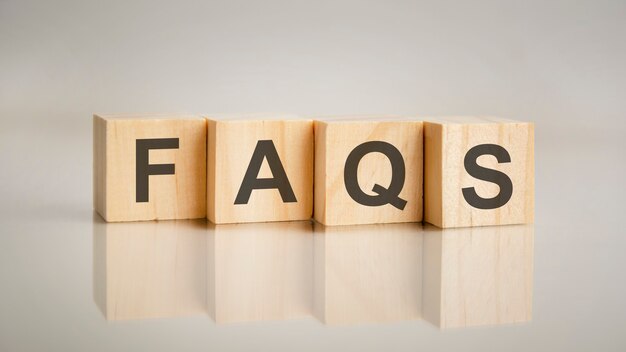 Four wooden cubes with letters FAQS. Business marketing concept. Reflection of the caption on the mirrored gray surface of the table