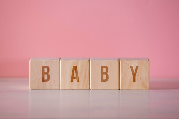 Four wooden cubes with the written word quotbabyquot on pink background