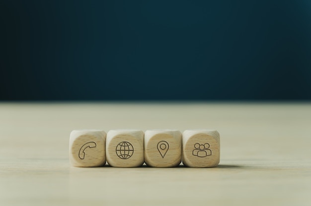 Photo four wooden dices with contact and information icons on them placed in a row. over blue background with copy space.